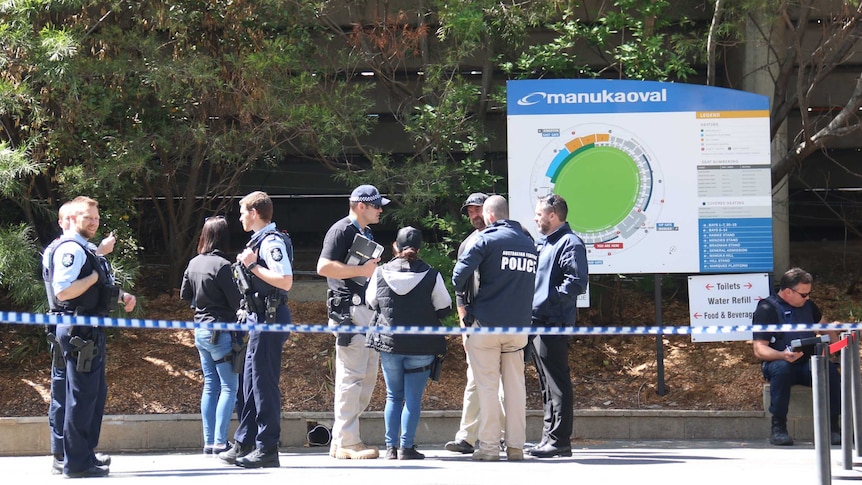 ACT police officers behind police tape at Manuka Oval.