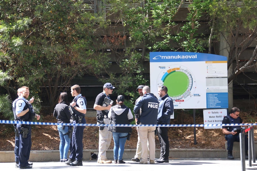 ACT police officers behind police tape at Manuka Oval.