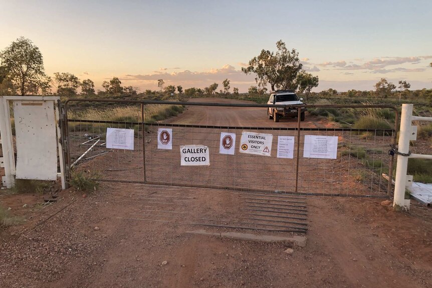 A bush track at dusk with a locked gate covered with 'closed' signs