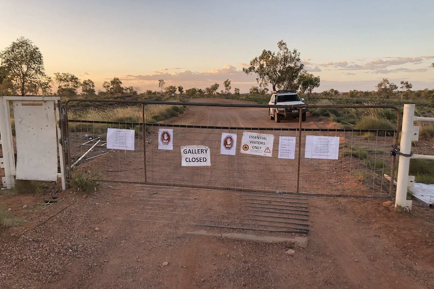 A bush track at dusk with a locked gate covered with 'closed' signs
