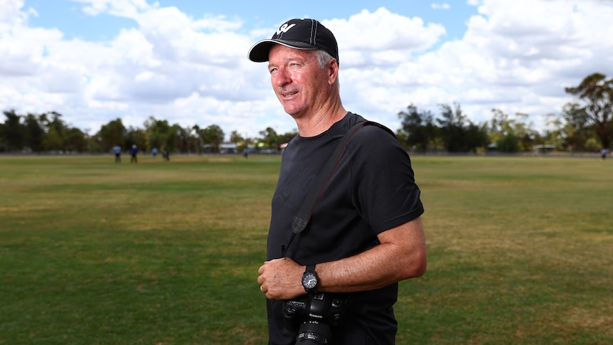 A man in a cricket field with a camera