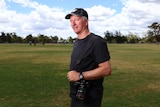 A man in a cricket field with a camera