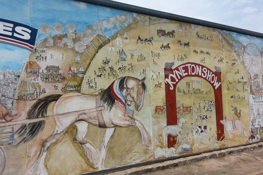 A mural of a horse galloping across a showground