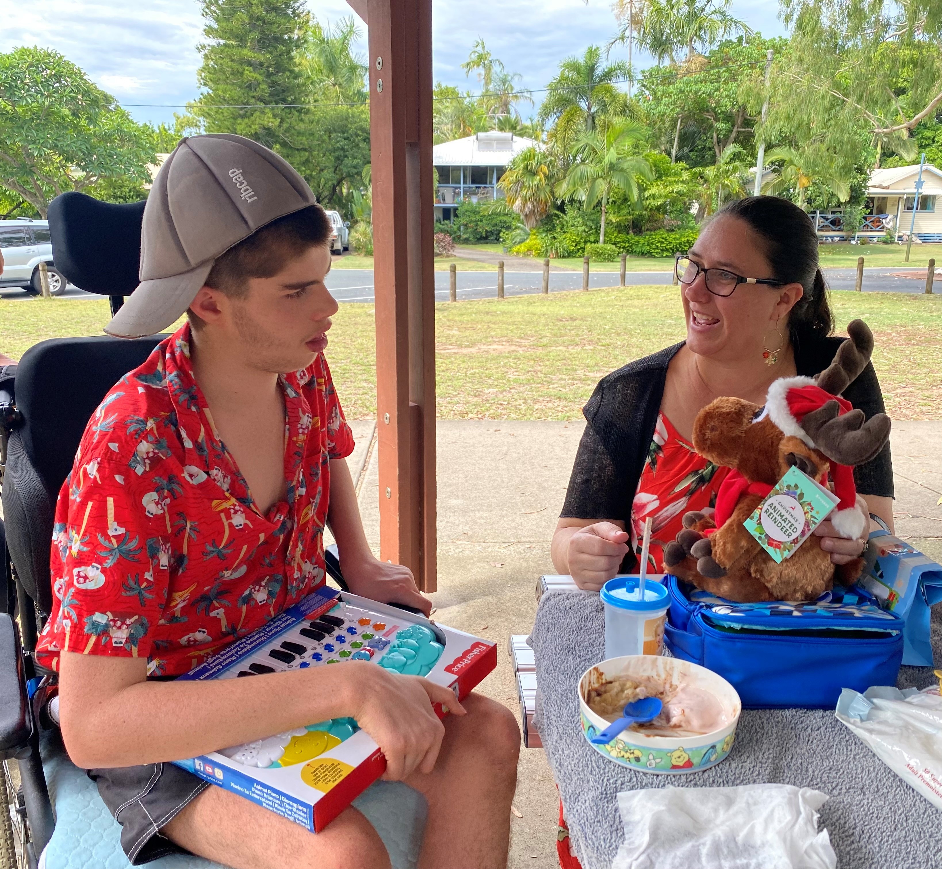 Nic Bennett wears a Christmas shirt and looks at his presents at a park table