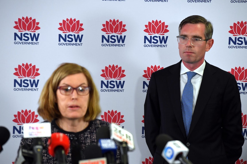 a man wearing glasses standing behind a woman 