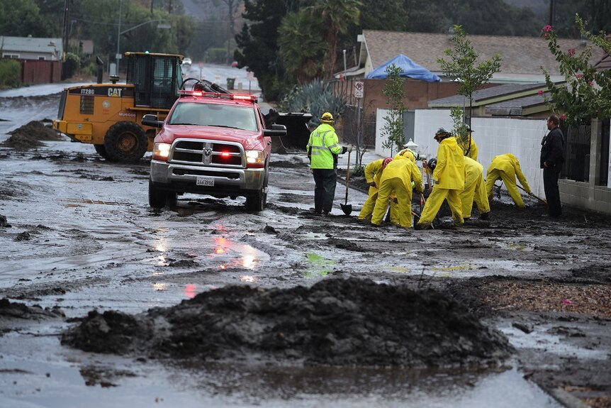 Emergency workers clear mud from a residential road.