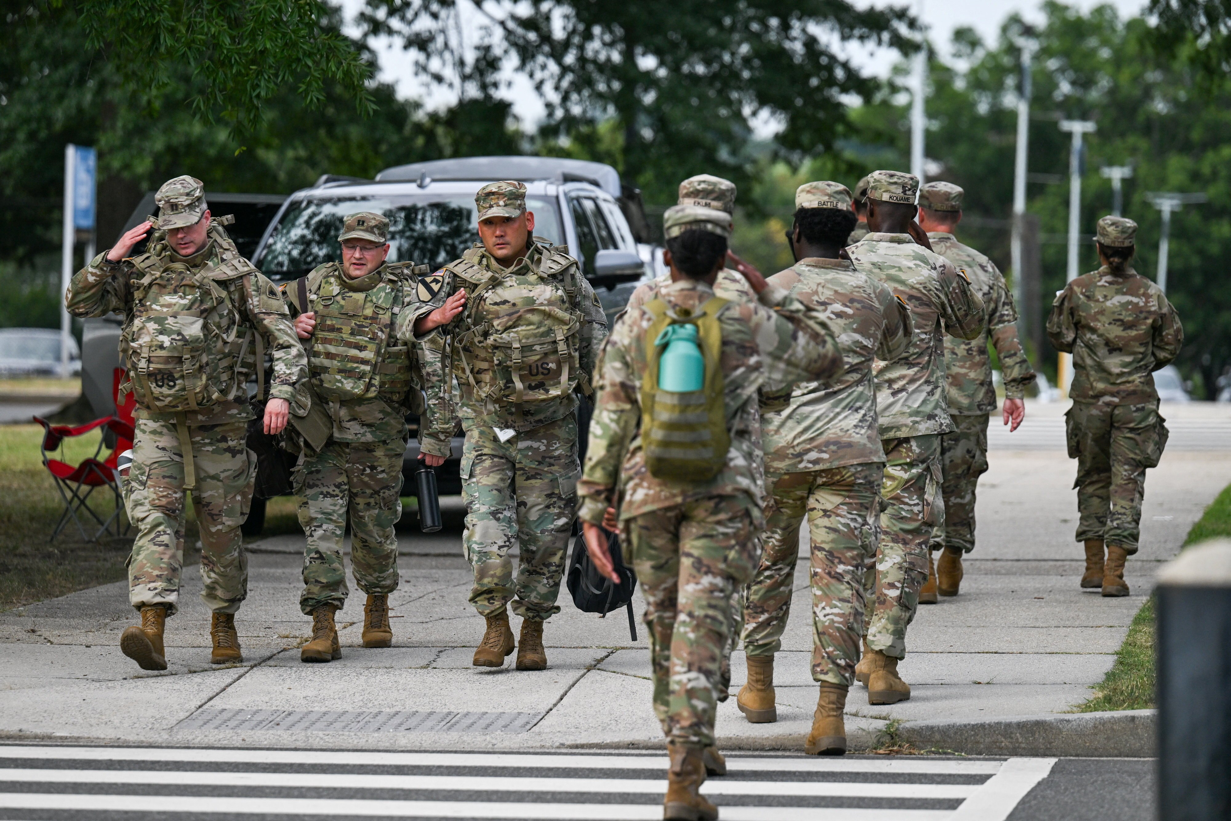 Troops in camouflage fatigues walk along a zebra crossing.