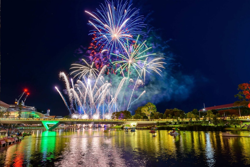 Fireworks explode over a bridge with people standing on it at night