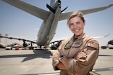 Woman in RAAF uniform standing beneath the rear of a military plane