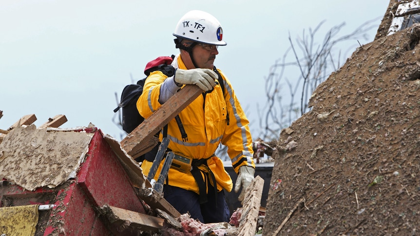 A rescue worker sifts through rubble in a residential area in Moore, Oklahoma following a deadly tornado.