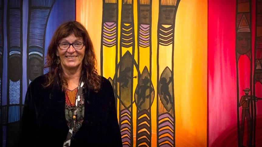 Portrait of Bronwyn Bancroft standing in front of her painting What the Trees Have Seen