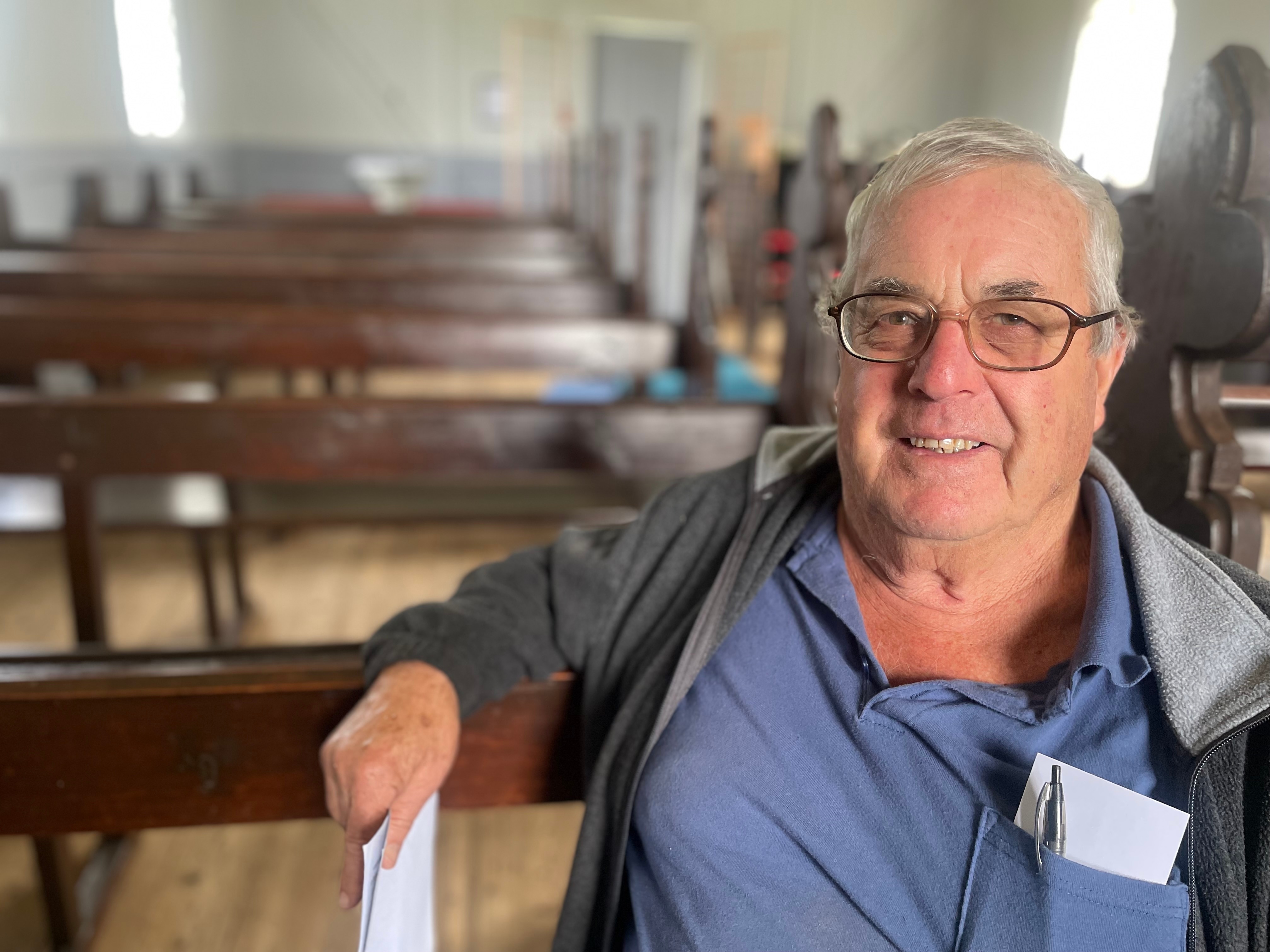 man smiling wearing glasses sitting in church pew