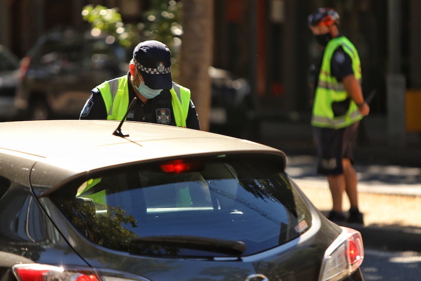 Police officer talking to a driver, another officer in bachground in Brisbane COVID-19 lockdown