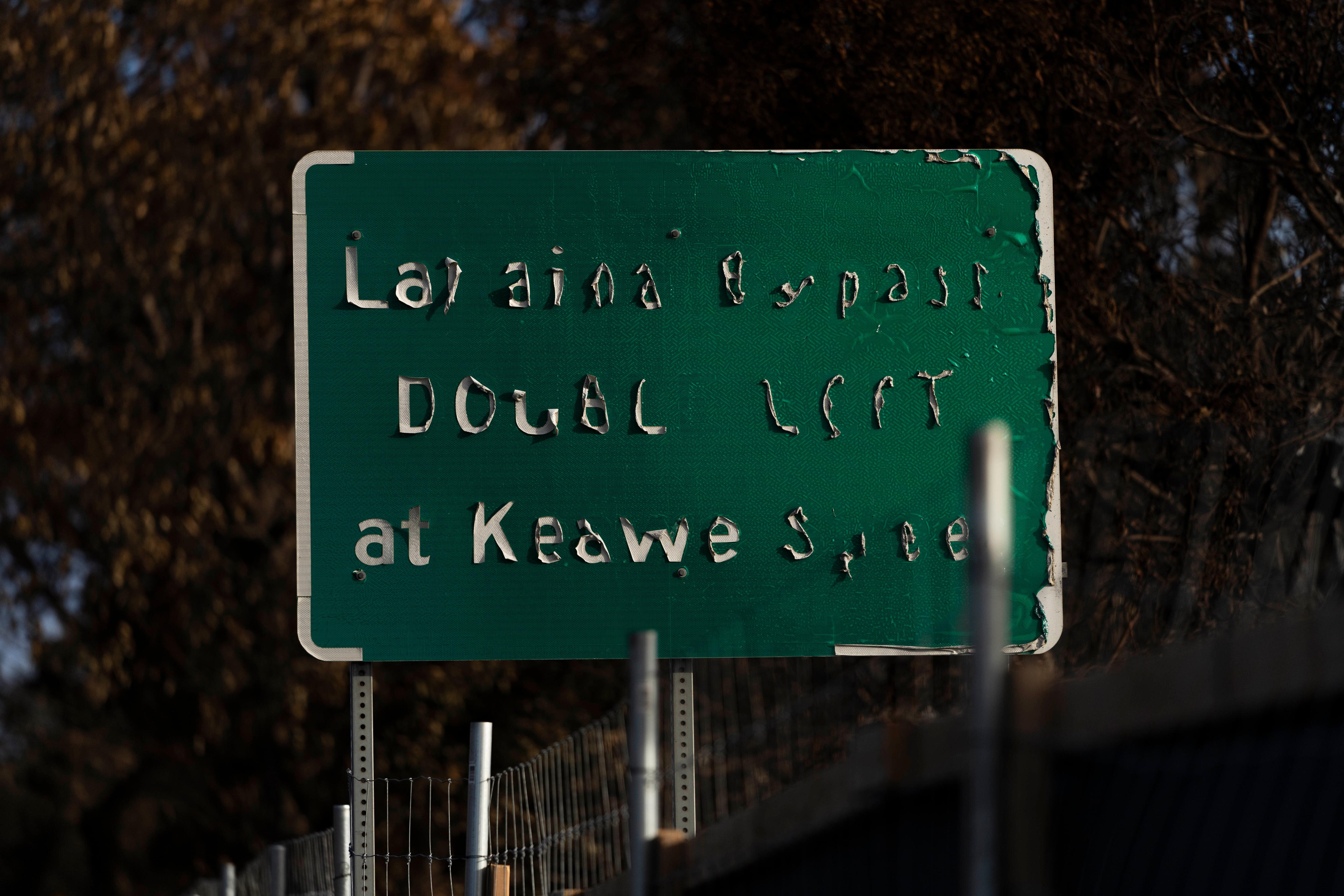 A green road sign with the white letters peeling off