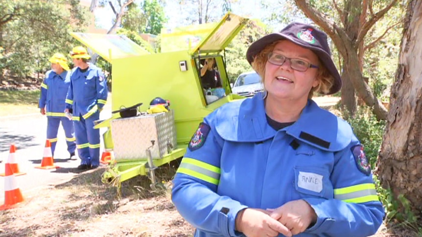 Community Fire Unit volunteer Anne Goyne in front of a firefighting trailer.