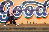A man walks past a mural with the word "good", depicting a worker interested in building good team culture.