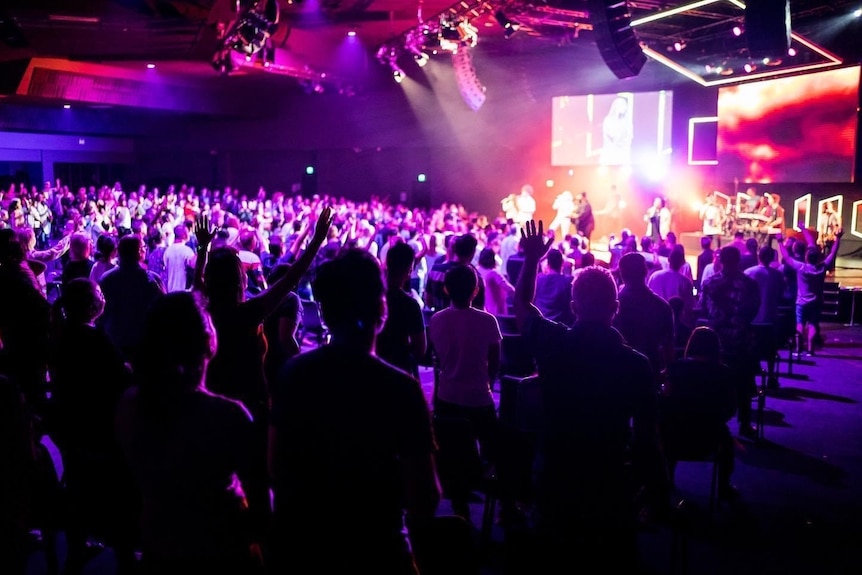 A large church amphitheatre with a stage and musicians performing 