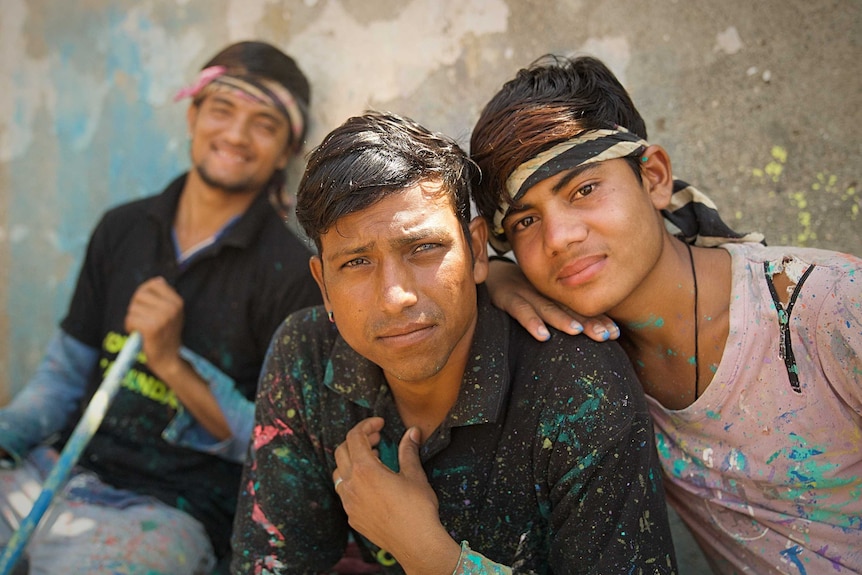 Men help paint a Mumbai slum.