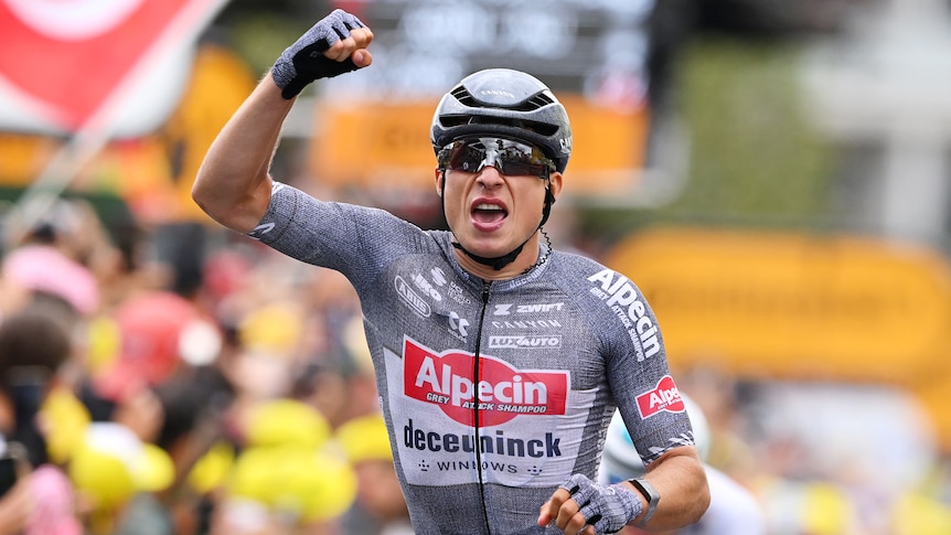 Jasper Philipsen raises his right fist after winning stage 13 of the Tour de France.