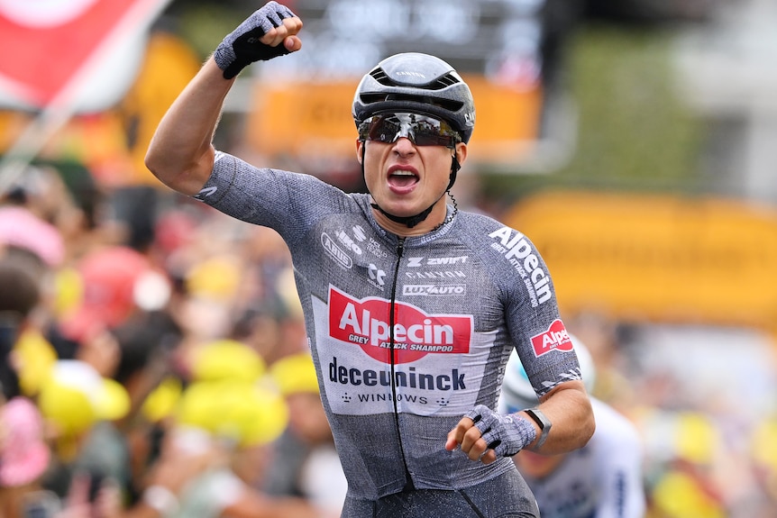 Jasper Philipsen raises his right fist after winning stage 13 of the Tour de France.