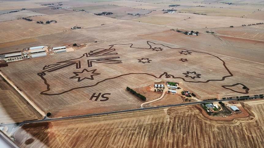 An aerial shot of a paddock with a huge map of Australia tilled into it.