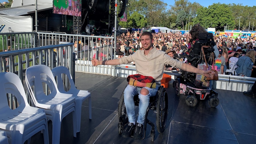 Jacob in wheelchair on platform in front of festival crowds