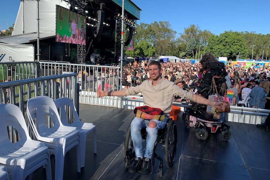 Jacob in wheelchair on platform in front of festival crowds