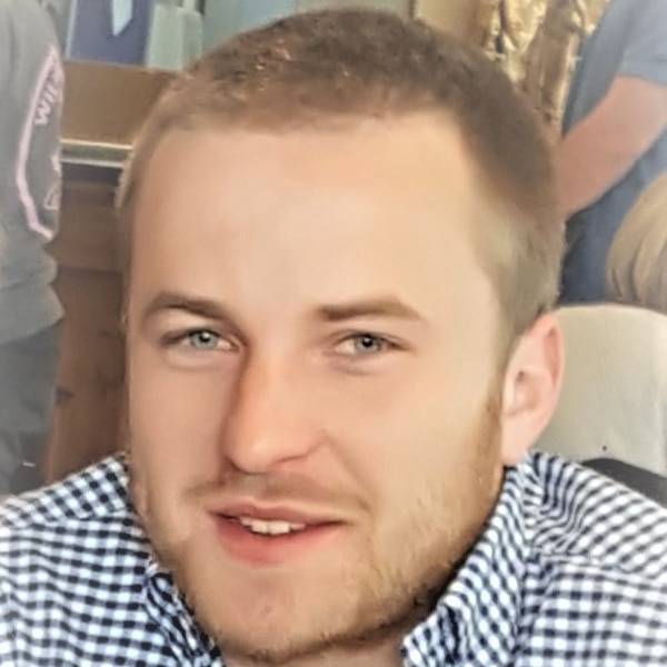 A man with short blond hair and a beard wearing a check shirt