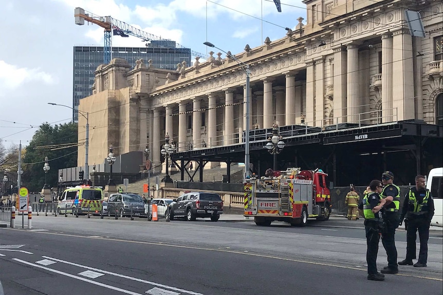Ambulance, police cars and fire trucks parked on Spring Street near the steps of Victorian Parliament.
