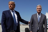 President Donald Trump holds the arm of Robert O'Brien as they stand on an airport tarmac.