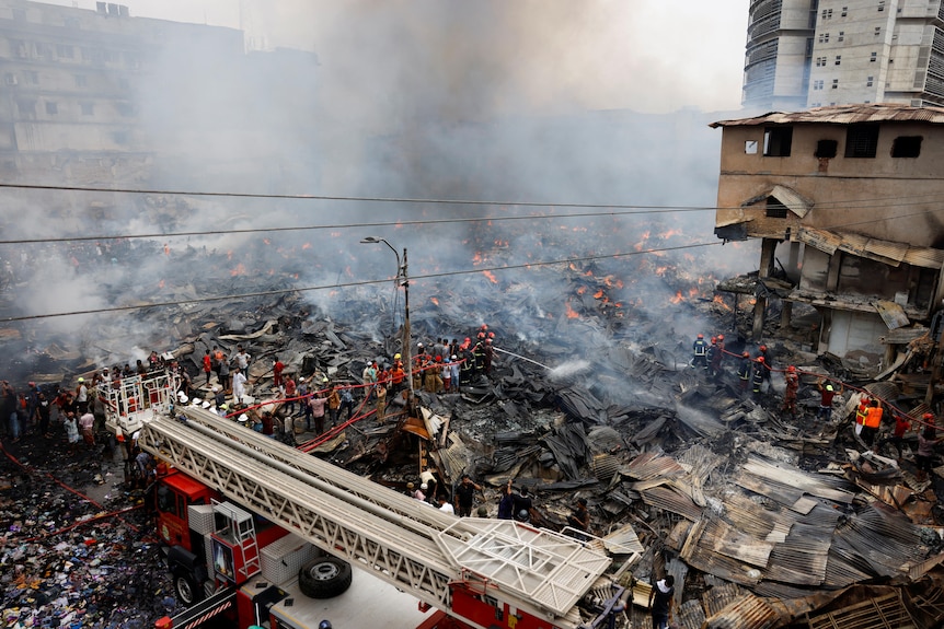 A fire truck is parked and is surrounded by buildings destroyed by fire. 