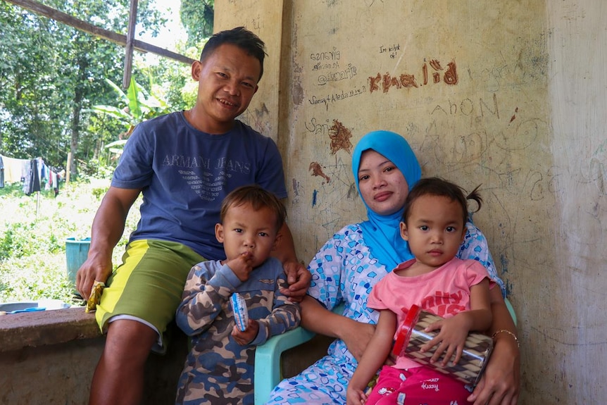 Two parents sitting holding two of their children.