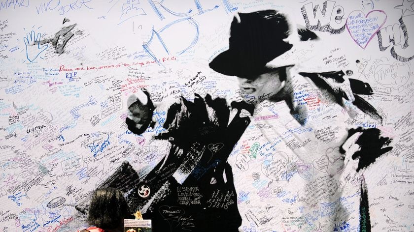 A Michael Jackson fan adds her message to a memorial poster outside Staples Centre