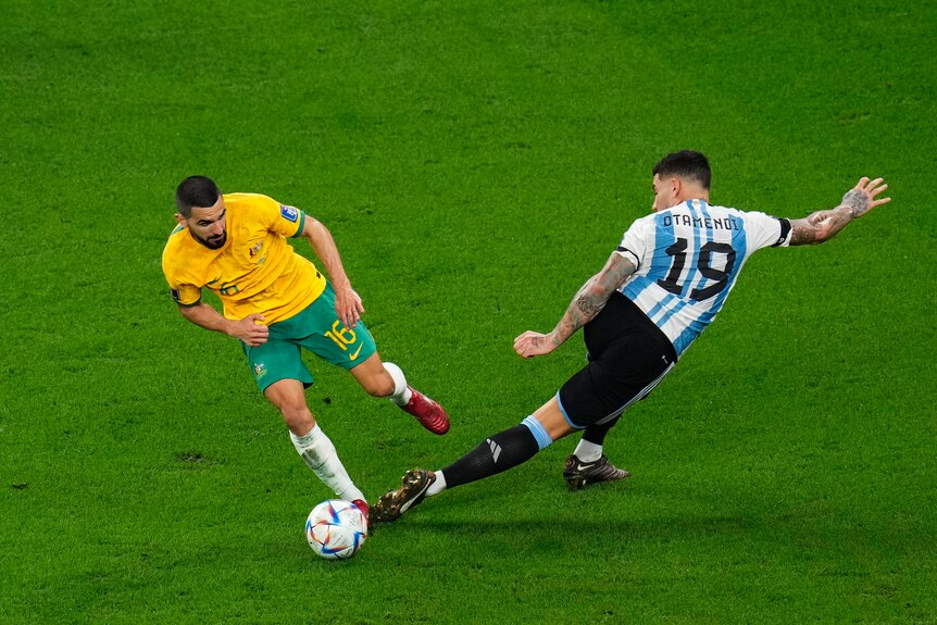 Socceroos' Aziz Behich dribbles past Argentina's NIcolas Otamendi, who is twisted in a strange position at the World Cup.