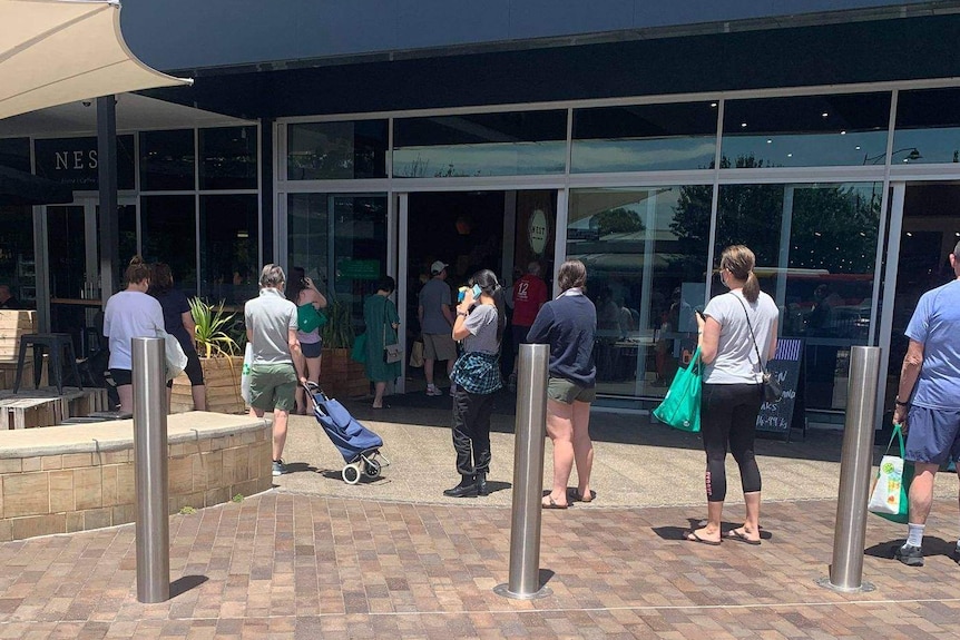 People line up in front of a Woolworths supermarket and shopping centre