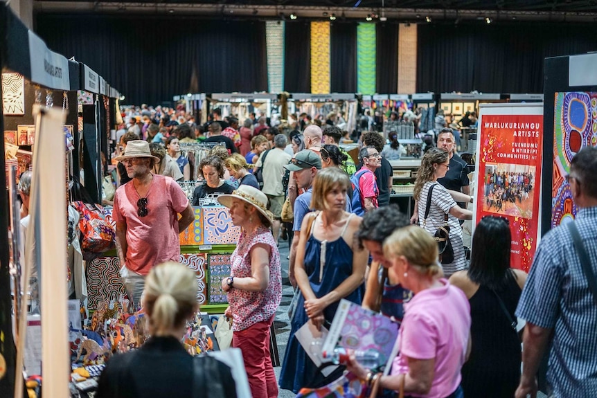 A packed Darwin Convention Centre with shoppers browsing art stalls.