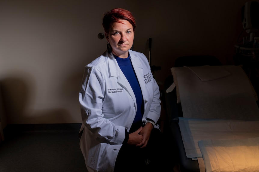 A woman sits next to a hospital bed.