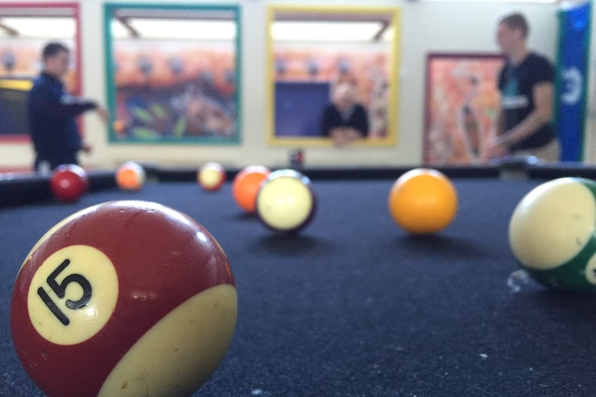 Two teenagers in conversation while playing pool