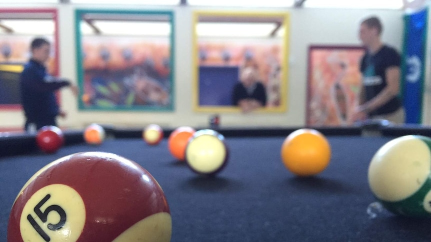 Two teenagers in conversation while playing pool