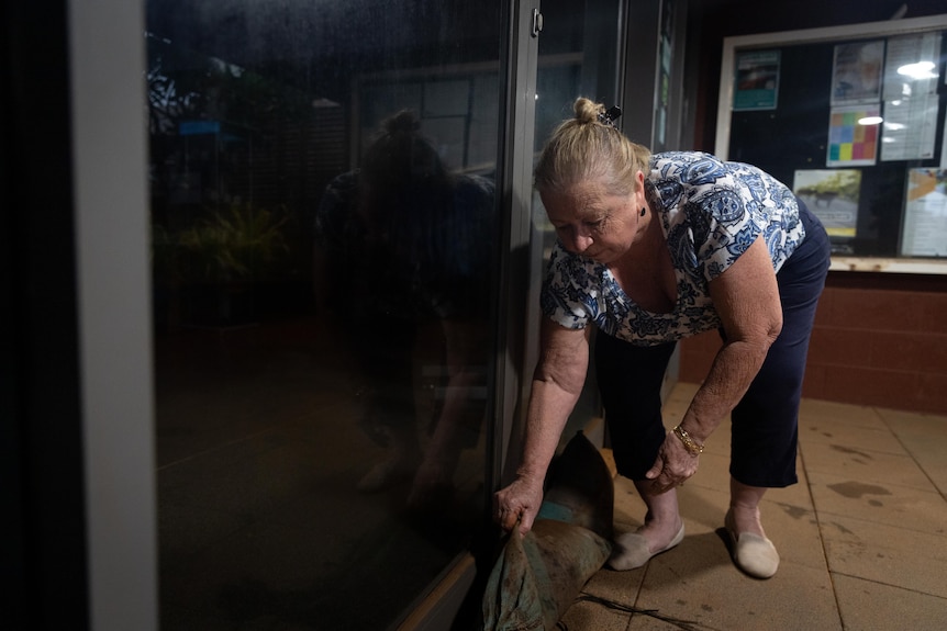 A woman sandbagging a door