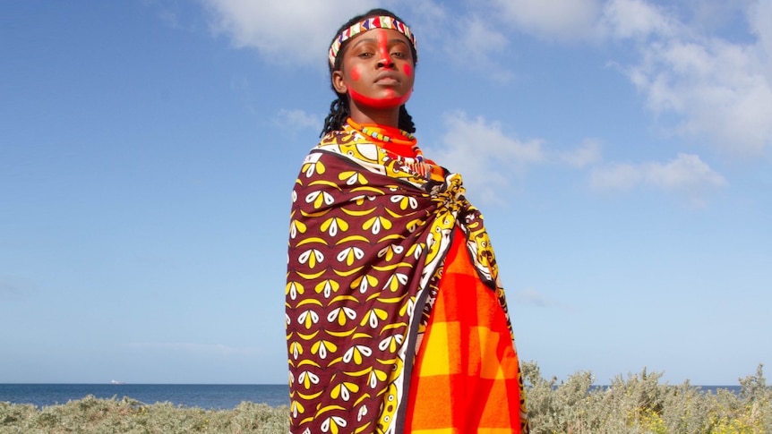 A 2022 press shot of Elsy Wameyo dressed in traditional Kenyan clothes against a blue sky background