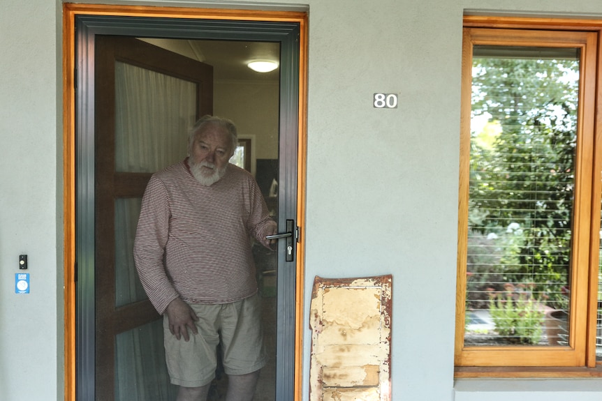 Christopher Whitehead standing just behind his front screen door.