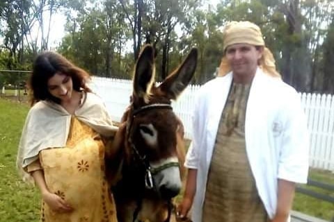 A woman and man in nativity costumes, with a donkey.