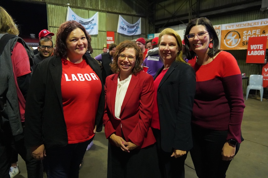 Four women wearing red inside a room