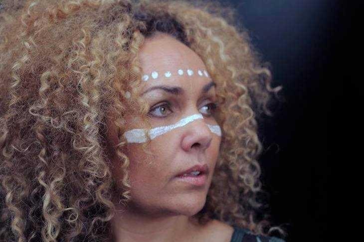 A women looking into the distance with Aboriginal art on her face. 