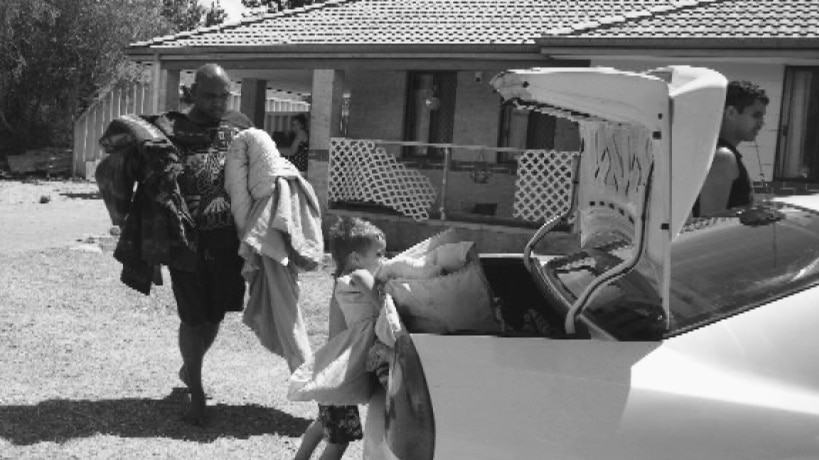 Man and boy pack blankets into car.