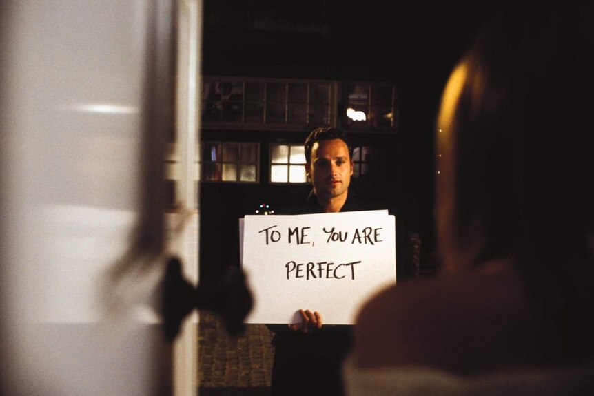 Screen shot from Love Actually movie where Andrew Lincoln holds a card saying "To me, you are perfect"