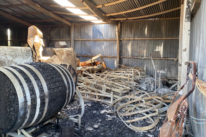 A bushfire-damaged shed with the remains of wine barrels.