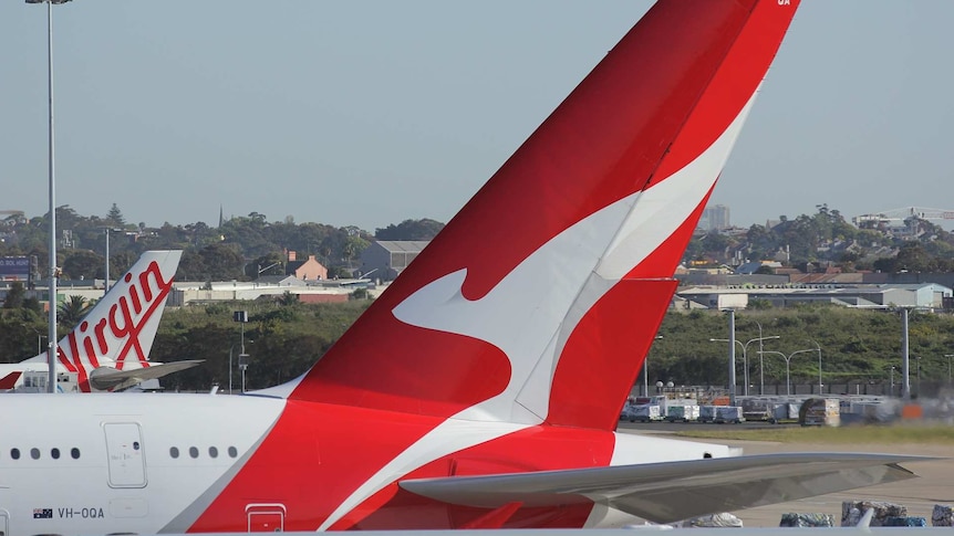 A Virgin Australia plane and a Qantas plane sit on a runway.