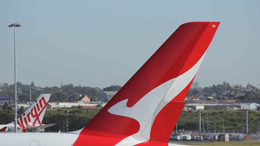 A Virgin Australia plane and a Qantas plane sit on a runway.